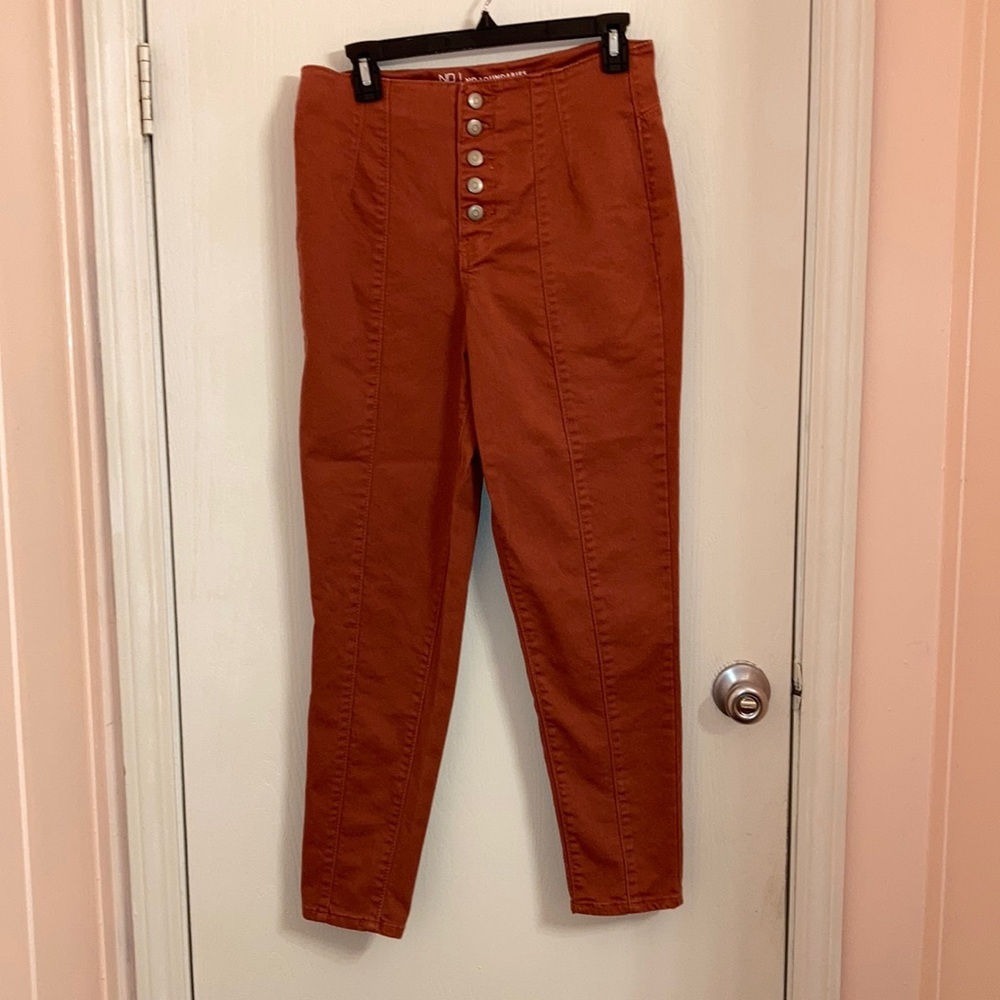 Terracotta colored jeans with buttons up the front